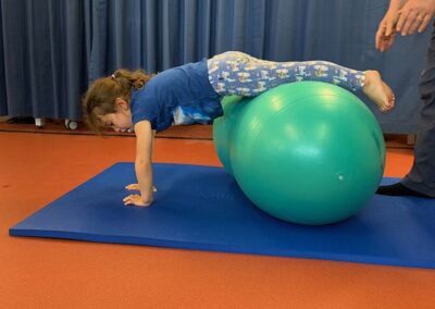 child having fun during treatment in a specialist physiotherapy session strengthening arms